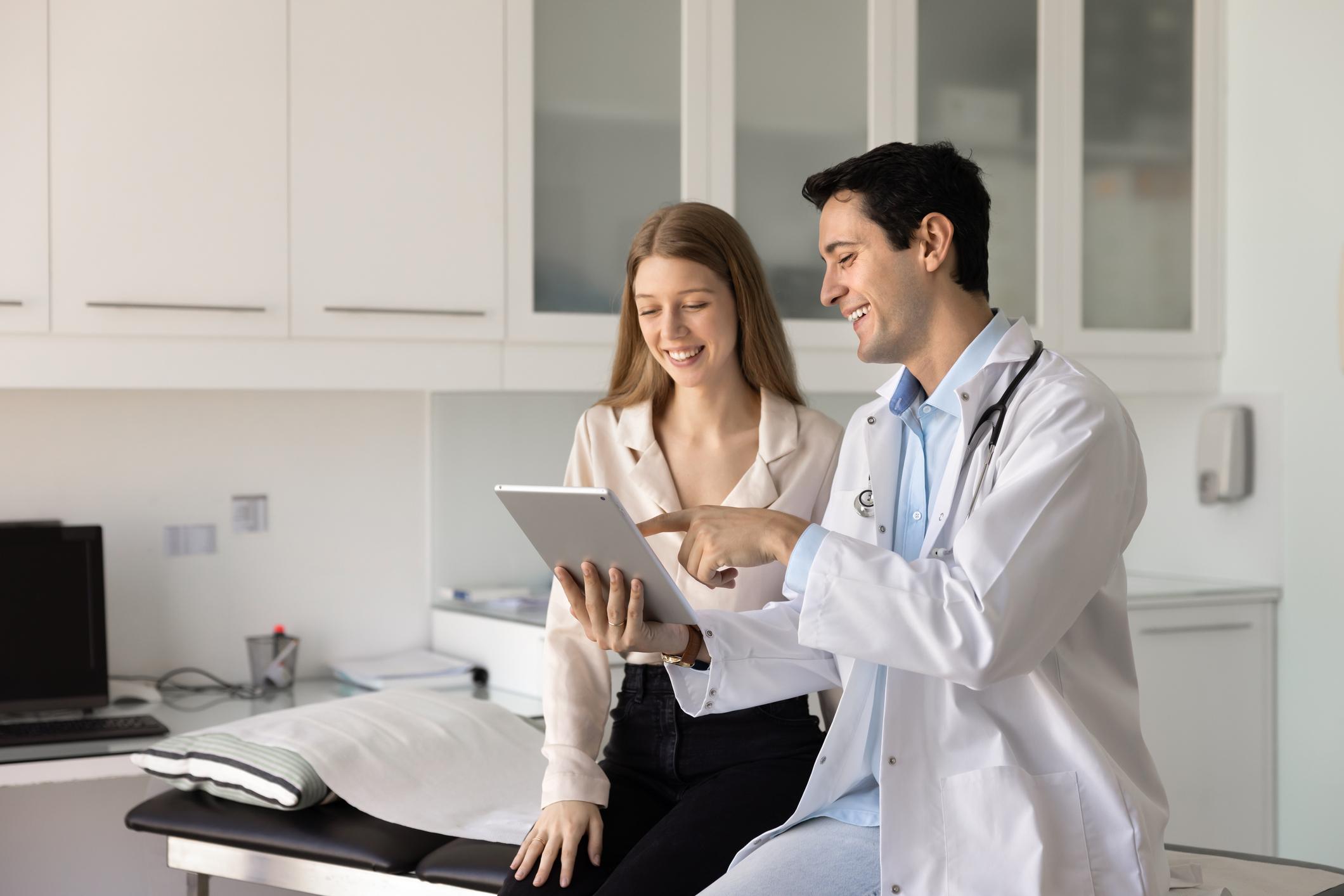 Physician reviewing a patient's digital diagnostic panel on a tablet in a modern clinical office